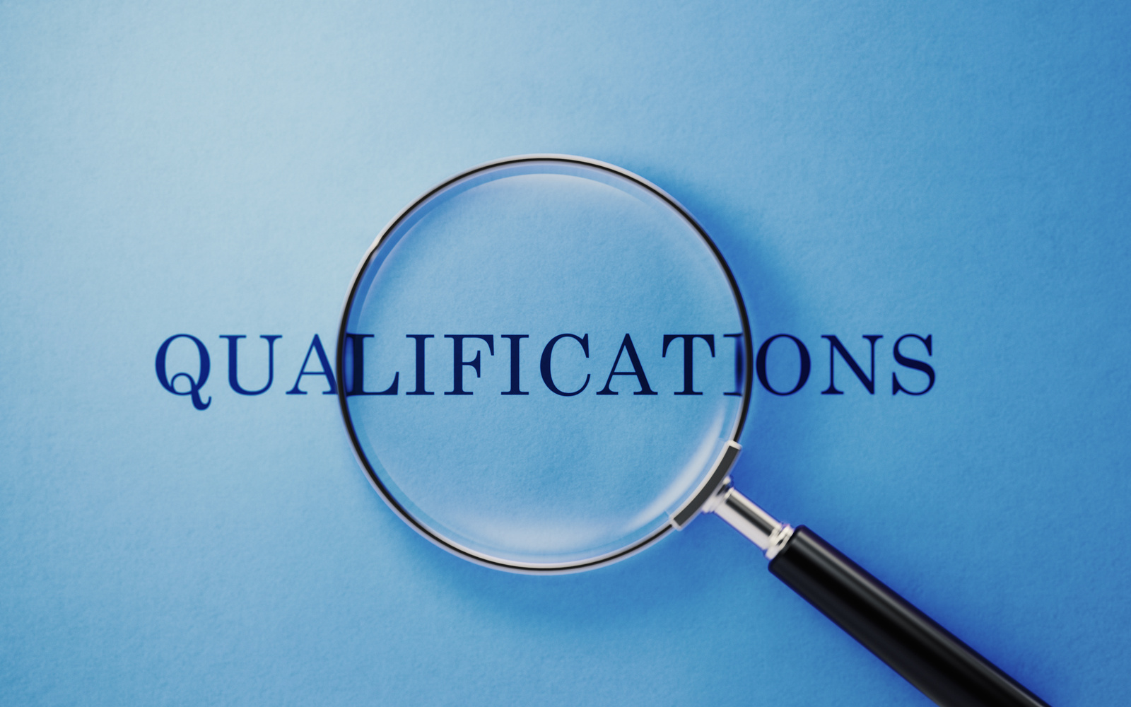 Magnifier And Qualifications Text On Blue Background